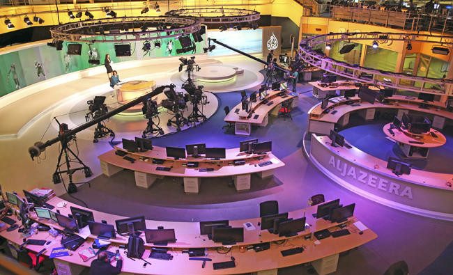 In this Jan. 1, 2015, file photo, staff members of Al-Jazeera International work at the news studio in Doha, Qatar. (AP Photo/Osama Faisal, File)
