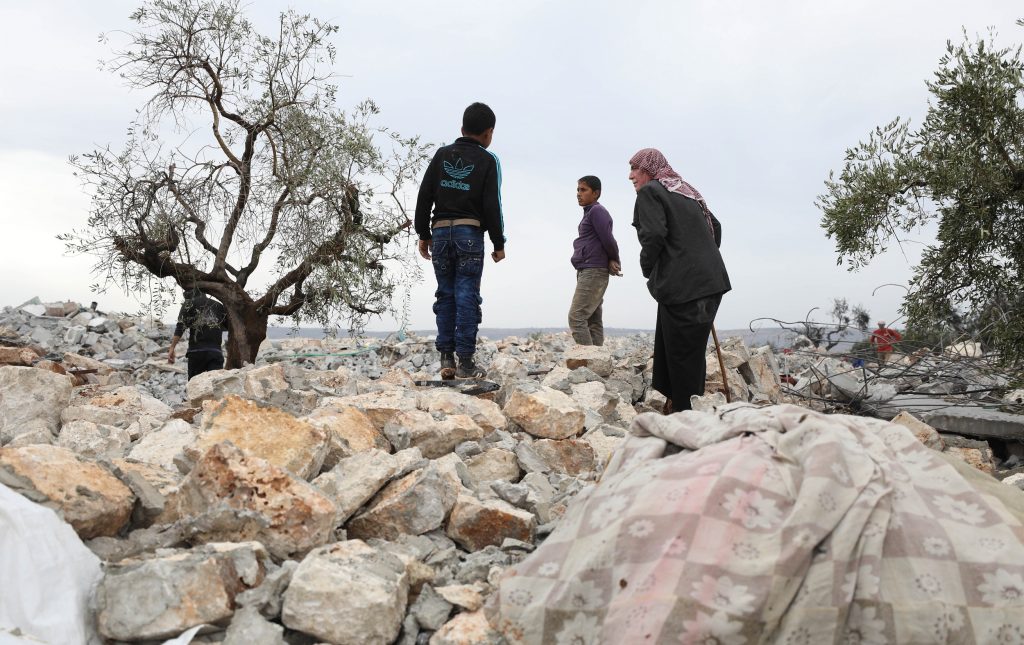 A picture taken on October 28, 2019 shows Syrians sifting through the rubble at the site of a suspected US-led operation against Daesh leader Abu Bakr al-Baghdadi the previous day. (AFP)