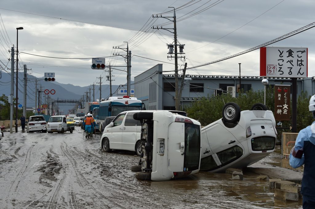 Overturned vehicles sit on the side of a muddy road in the aftermath of Typhoon Hagibis in Nagano on October 14, 2019. (AFP)