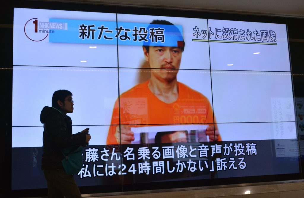 A pedestrian looks at a large screen showing television news reports about Japanese hostage Kenji Goto in Tokyo on January 28, 2015. (AFP)