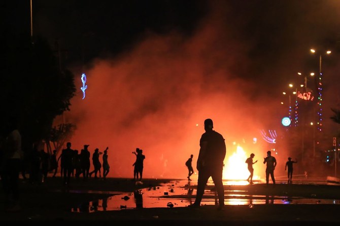 Iraqi protesters burn items to block the road as they clash with security forces in Karbala on Sunday. (AFP)