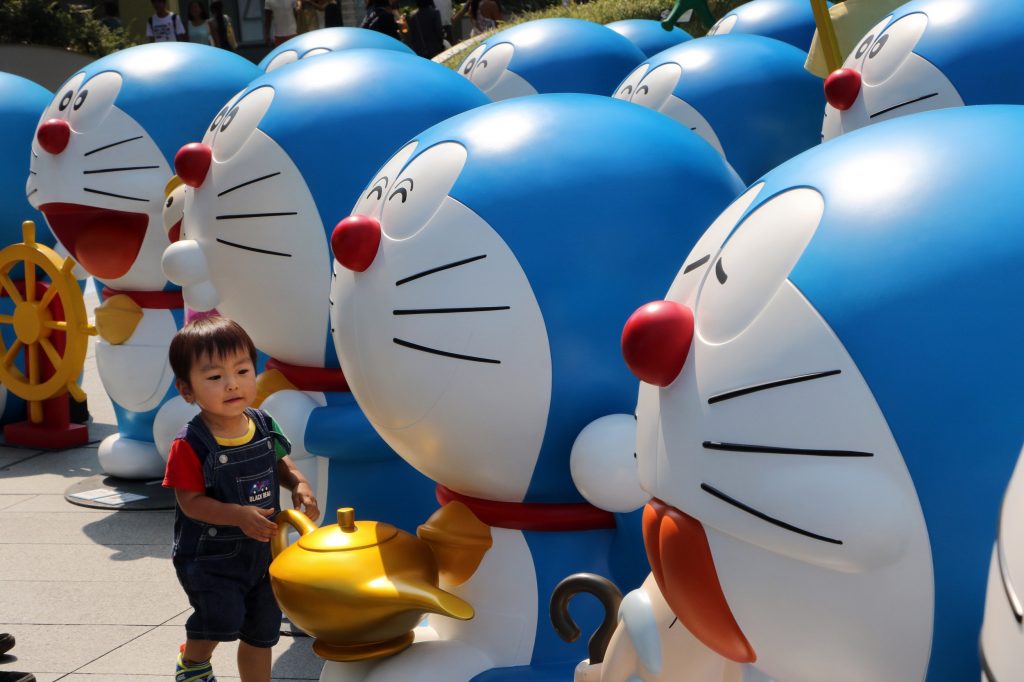 A child plays amid figures of anime manga character Doraemon displayed at Tokyo’s Roppongi Hills shopping and business complex on July 27, 2015. (AFP)