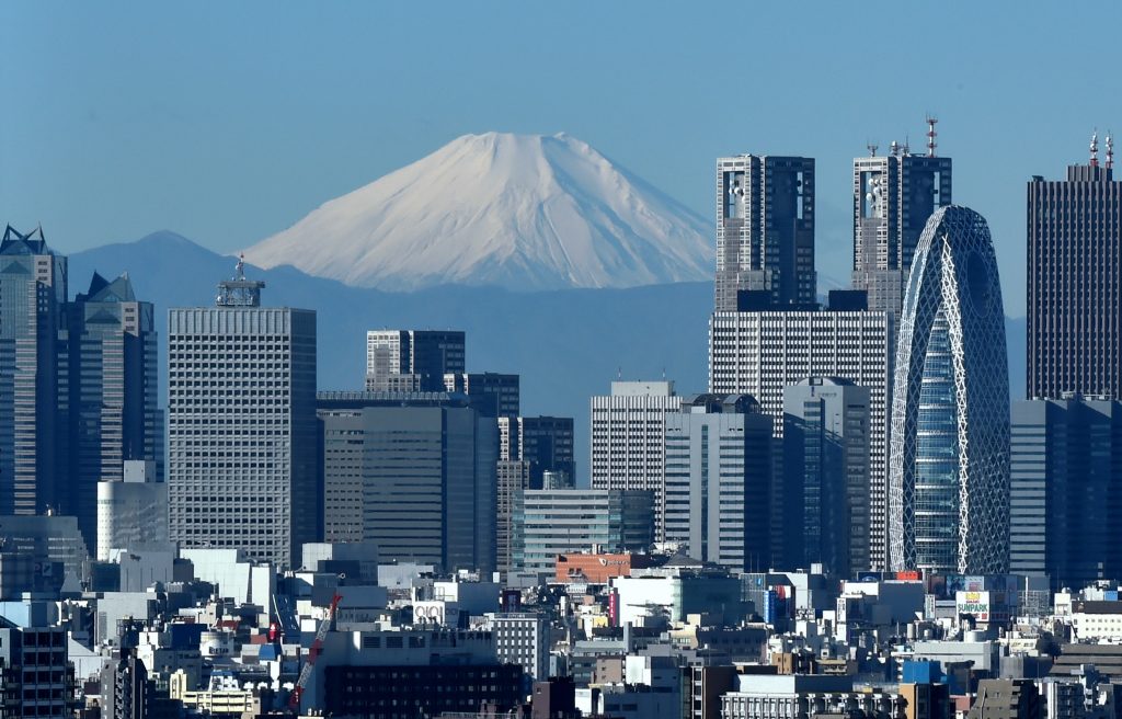 Japan’s highest mountain, Mount Fuji (C) is seen behind the skyline of the Shinjuku area of Tokyo on December 6, 2014. (AFP)