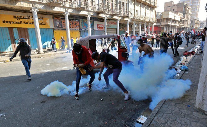 Anti-government demonstrators react to tear gas fired by Iraqi riot police during clashes in al-Rashid Street, Baghdad, Iraq, Sunday, Nov. 17, 2019. (AP)