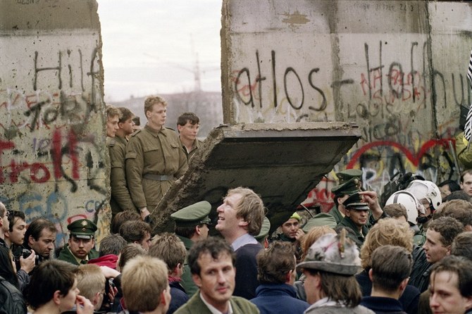 West Berliners crowd in front of the Berlin Wall early November 11, 1989 as they watch East German border guards demolish a section of the wall in order to open a new crossing point between East and West Berlin. (AFP)