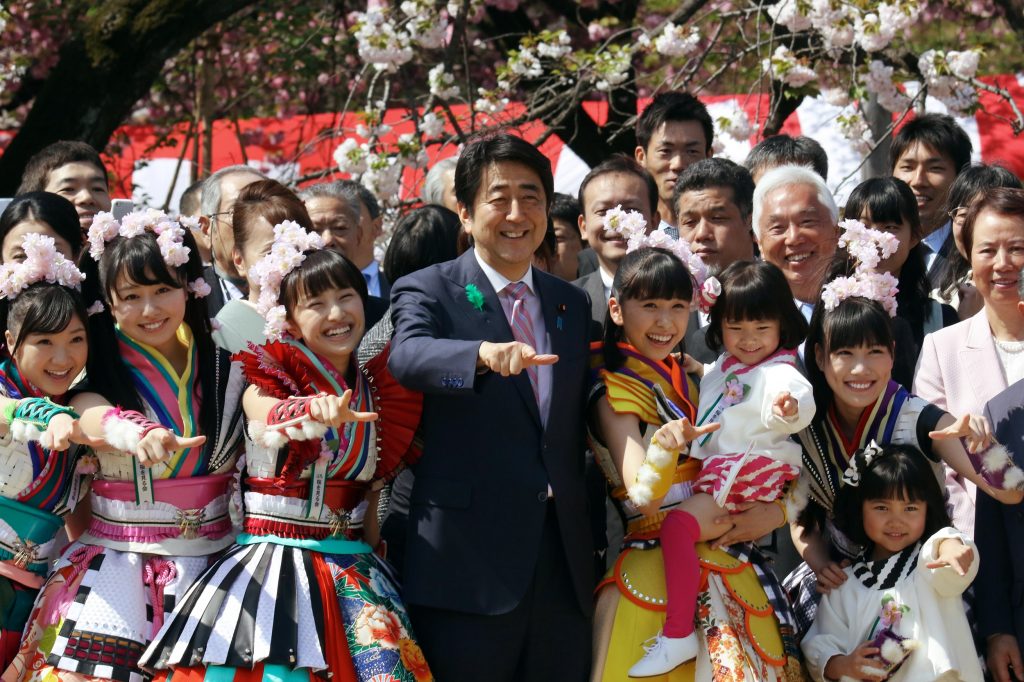 Shinzo Abe (C) poses with members of Momoiro Clover Z for a group picture during the cherry blossom viewing party in Tokyo on April 18, 2015. (AFP)