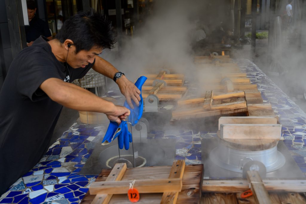 A cook prepares food using the water vapor from the hot springs (Onsen) in Beppu, near Oita on September 23, 2019. (AFP)