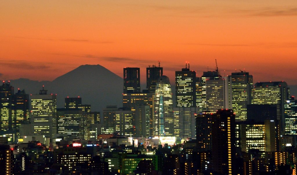 Japan’s highest mountain Mount Fuji (top L) is seen behind the skyline of the Shinjuku area of Tokyo at sunset on November 27, 2014. (AFP)