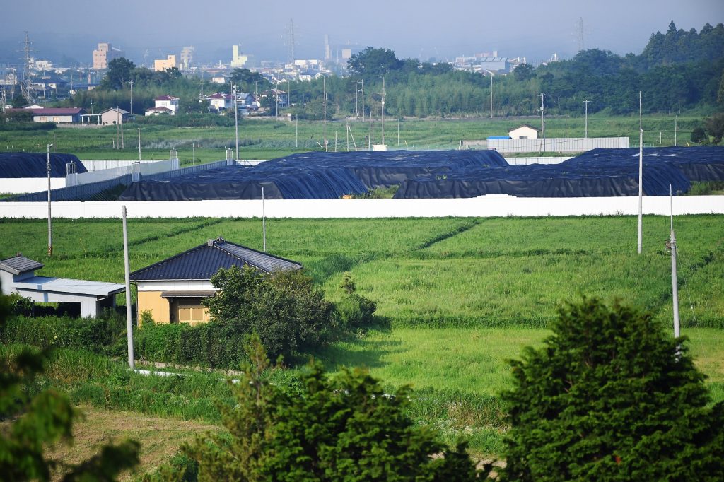 Radiated surface soil covered by black tarps at a decontaminated field in Futaba, Fukushima prefecture, on August 2, 2019. (AFP)