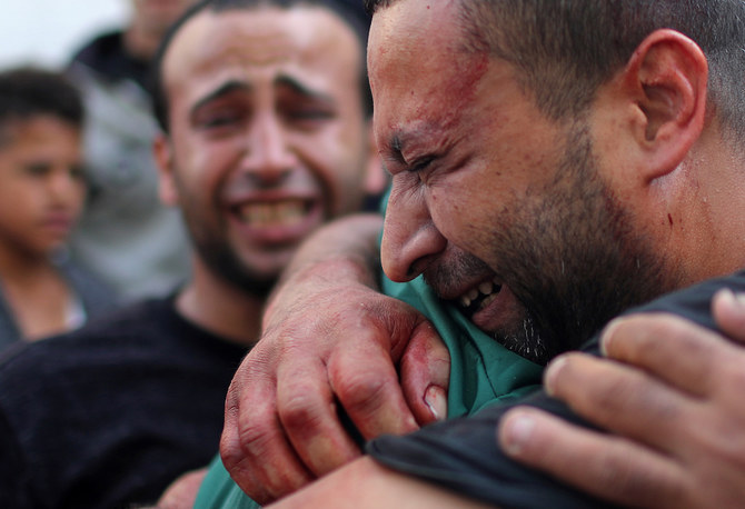 A Palestinian man, stained with the blood of his relative, is comforted as he reacts at Al-Shifa hospital in Gaza City Nov.13, 2019. (Reuters)