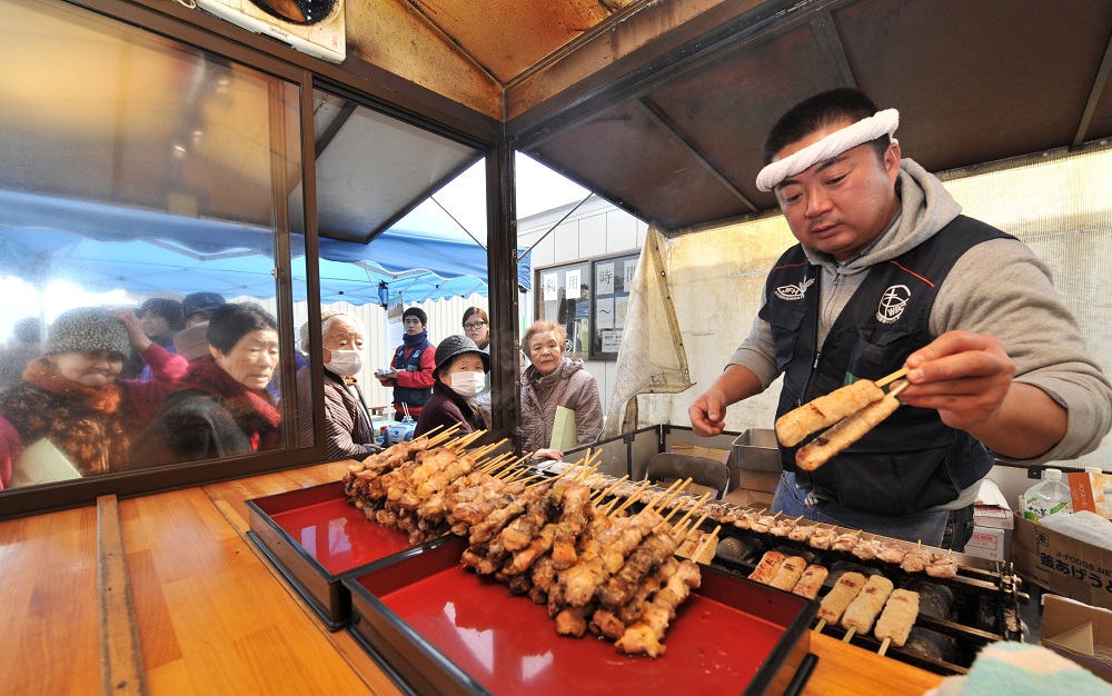 This photo taken on February 10, 2012 shows clergyman Koji Kumada preparing skewered chicken (yakitori) for tsunami victims living in temporary housing in Watari, Migagi prefecture. (AFP)