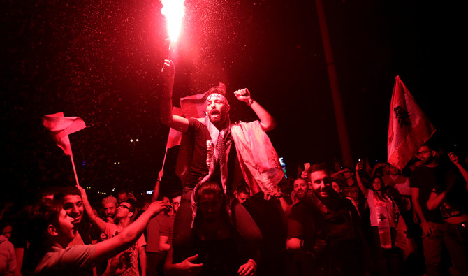 A protester holds a flare as he chants slogans at a demonstration following a broadcasted interview by Lebanese President Michel Aoun