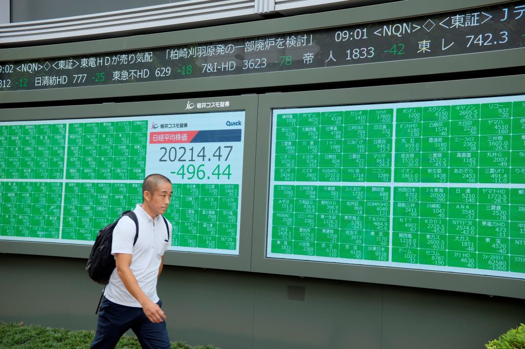 A pedestrian walks in front of an electric quotation board displaying the numbers on the Nikkei 225 index at the Tokyo Stock Exchange in Tokyo on August 26, 2019. (AFP)