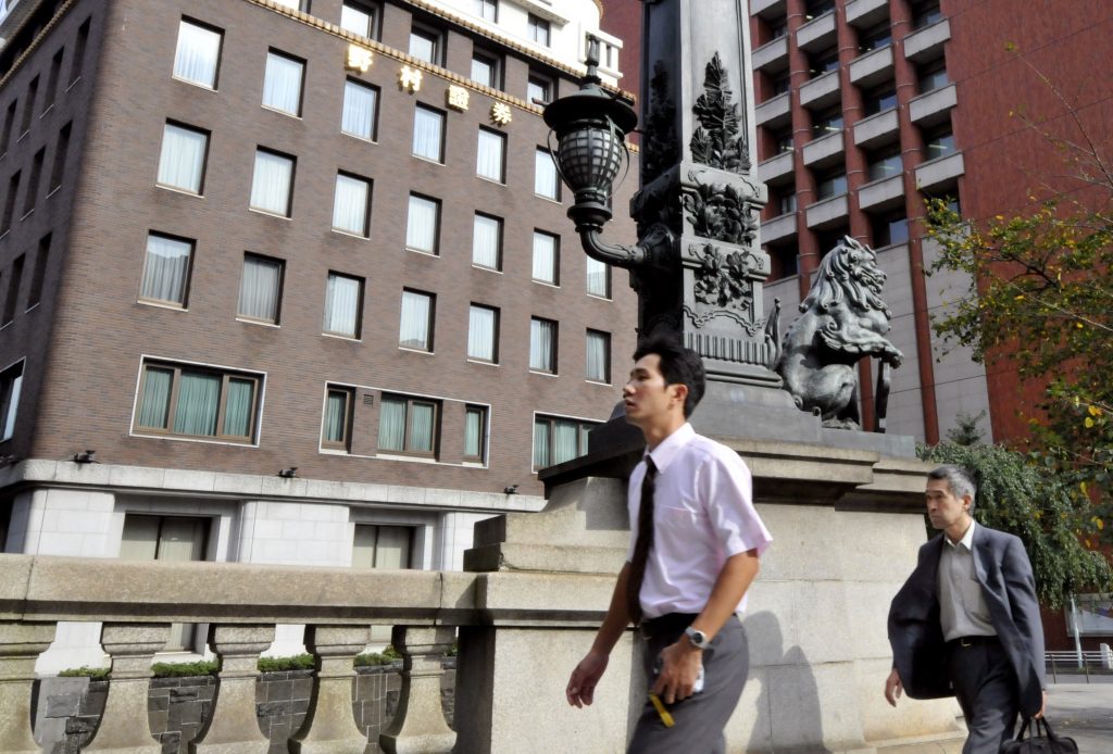 Businessmen walking past the headquarters of Nomura Holdings in Tokyo on September 11, 2009. (AFP)