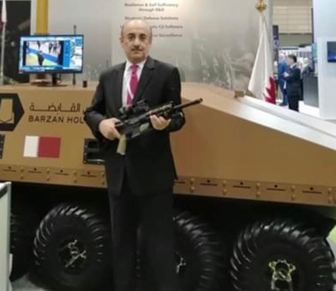 Hassan Al-Emadi, Ambassador of Qatar to Japan posing in front of the model and holding a Qatari made Bindig ARX rifle at DESI in Tokyo. (Supplied)