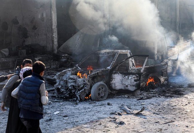 A woman is assisted as she walks past a burning car following a car bomb explosion at the industrial zone in the northern Syrian town of Tal Abyad. (File/AFP)