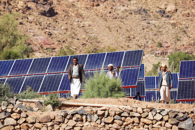 Farmers walk next to solar panels at a farm in Wadi Dhahr near Sanaa, in Yemen. (Reuters)