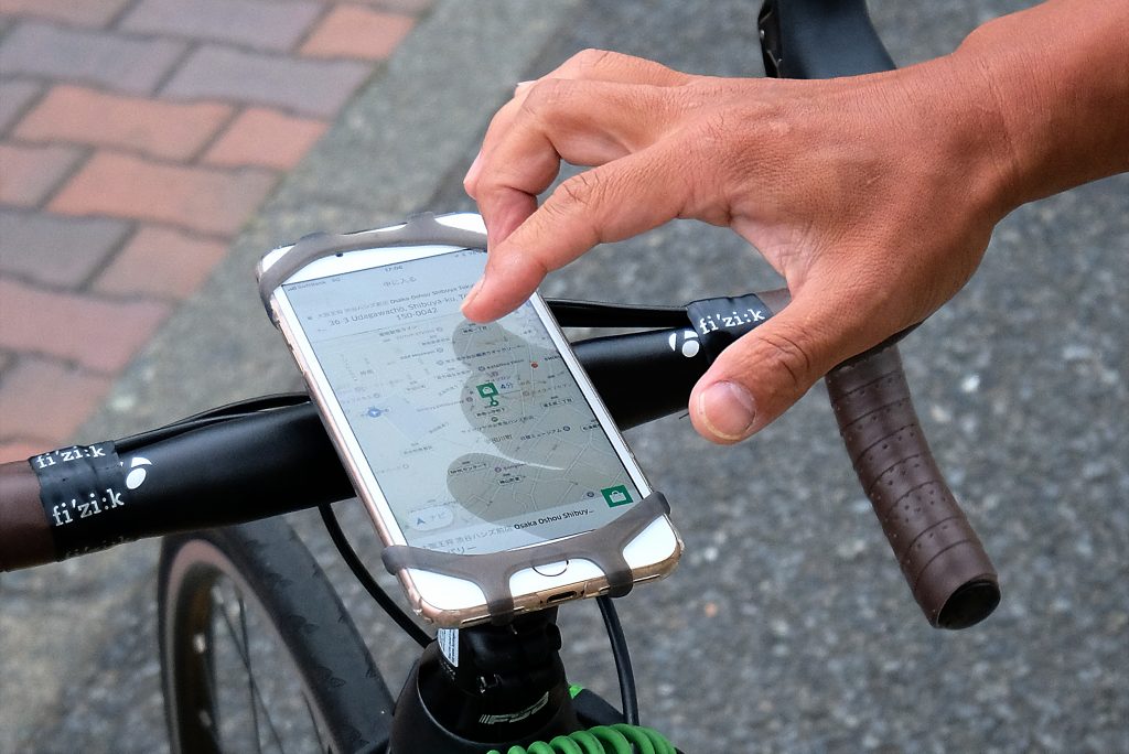 A man uses a smartphone attached to his bicycle to find a location to deliver an order of food to a customer for meal delivery service UberEATS in Tokyo's Shibuya shopping district. (AFP file)