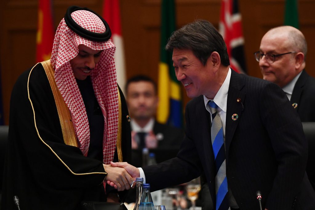 Japan's Foreign Minister Toshimitsu Motegi (R) shakes hands with Saudi Foreign Minister Prince Faisal bin Farhan to mark the handover to the Saudis as future hosts, at the end of the third plenary session of the G20 foreign ministers' meeting in Nagoya, Aichi prefecture on November 23, 2019. (AFP)
