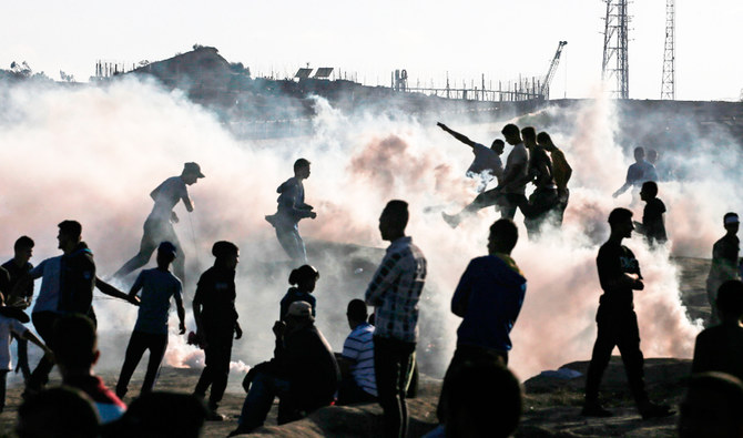 Palestinian protesters stand amid tear gas canisters fired by Israeli forces during a demonstration along the border with Israel east of Bureij in the central Gaza Strip on November 1, 2019. (AFP)