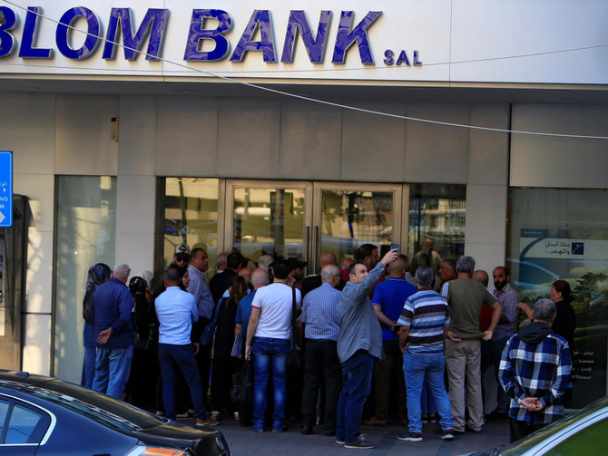 A man takes a picture with his mobile phone as people queue outside a branch of Blom Bank in Sidon, Lebanon November 1, 2019. REUTERS/Ali Hashisho