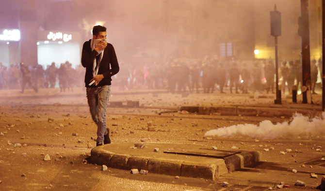 A protester covers his face from the tear gas that fired by the riot police during a clash amid anti-government protests in Beirut on Monday. (AP)