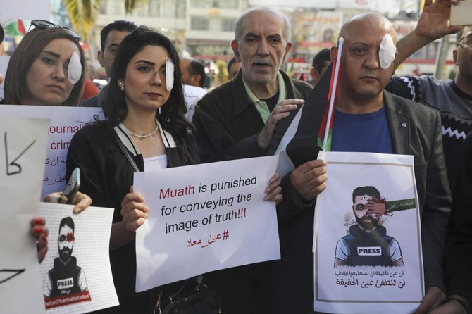 Palestinian journalists stand in solidarity with Palestinian cameraman Mu'ath Amarneh who days before was injured in his eye by a rubber bullet while covering clashes between Palestinian protesters and Israeli security forces in a West Bank demonstration. (AFP)