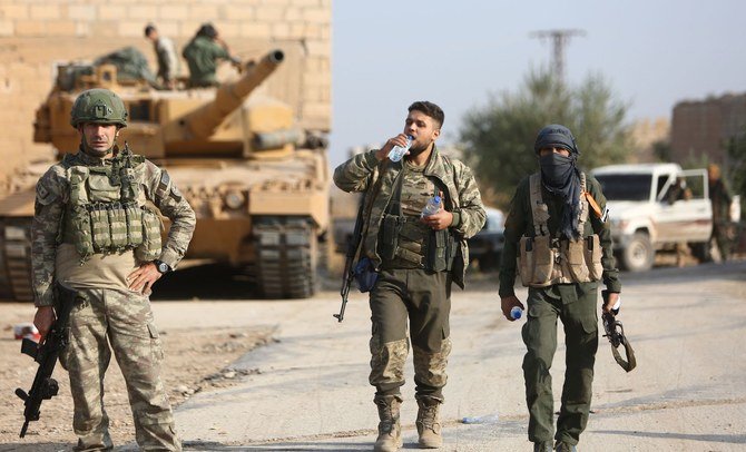 Turkish soldiers and a Turkey-backed Syrian fighter walk during a raid in a village east of Ras Al-Ain in northeastern Syria, on October 28, 2019. (AFP)