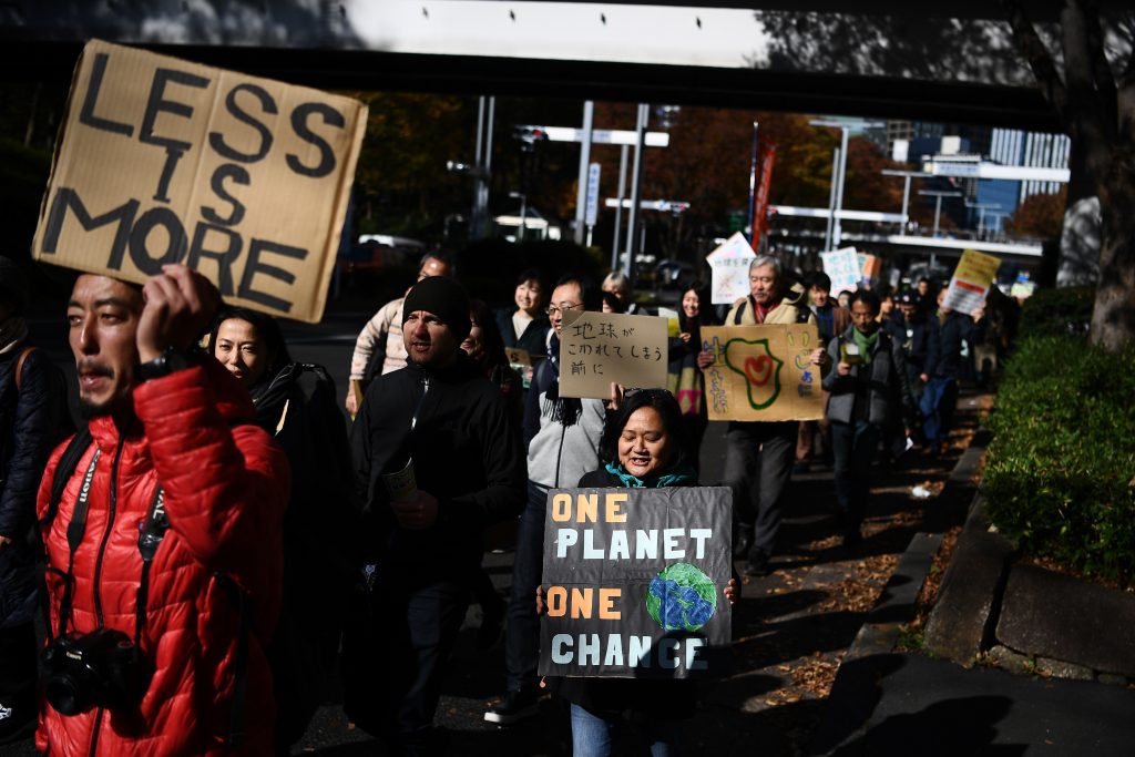 Participants hold up placards as they take part in call for action on climate change with a couple of hundred people during a march in Tokyo on November 29, 2019. (AFP)