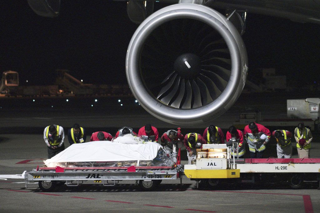 Airport workers bow to pay respect to the coffin of slain Japanese doctor Tetsu Nakamura at Narita International Airport in Narita, near Tokyo Sunday, Dec. 8, 2019. (AP)