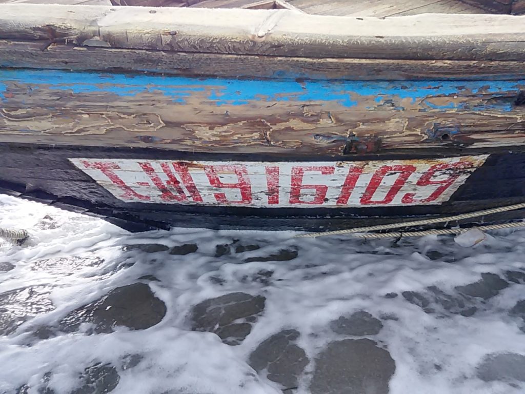 Numbers and letters are seen on a wooden boat containing human remains and suspected to be from North Korea, according to a Coast Guard official, along a shore of Sado island. (Reuters)