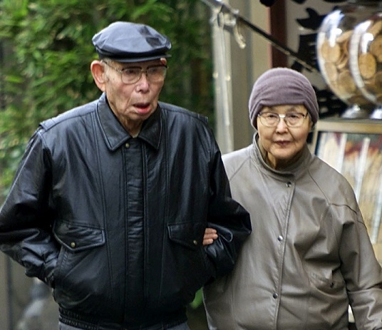 An elderly couple seen walking on the streets of Tokyo. For those aged between 40 and 64, health insurance bodies collect premiums, which are distributed to municipalities via the Health Insurance Claims Review & Reimbursement Services. (AFP/file)