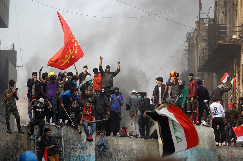 Iraqi demonstrators celebrate by a concrete barricade following the resignation of Prime Minister Adel Abdul-Mahdi's government, during a demonstration along Rasheed Street in the centre of the capital Baghdad, on November 29, 2019. (AFP)