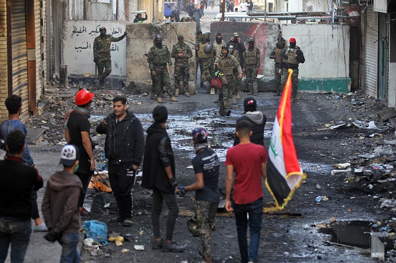 Members of the Iraqi security forces and anti-government protesters gather in front of a concrete barrier on al-Rasheed street in the capital Baghdad, during a lull in the anti-government protests, on December 5, 2019. (AFP)