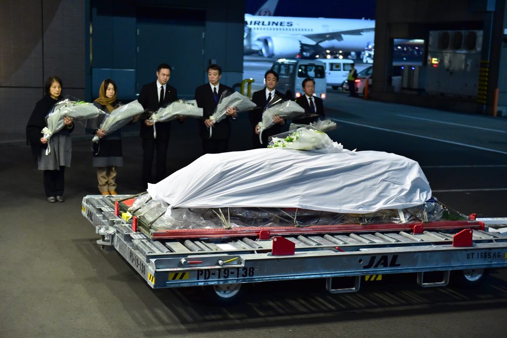 Government officials and relatives of late Japanese physician Tetsu Nakamura offer bouquets in front of his coffin at the Narita Airport in Chiba prefecture on December 8, 2019. (AFP)