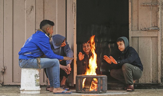 Palestinian youths warm themselves around a fire during heavy rain in Gaza City on December 27, 2019. (AFP)