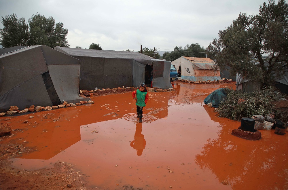 A girl walks through a rainwater puddle before tents in a flooded camp for displaced Syrians near North-eastern Syria. (AFP/file)