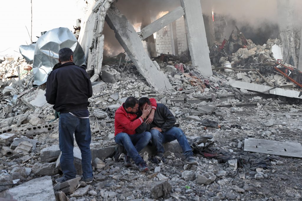 A Syrian man comforts another on the rubble of a building after a reported Russian airstrike on a popular market in the village of Balyun in Syria's northwestern Idlib province, on December 7, 2019. (AFP)