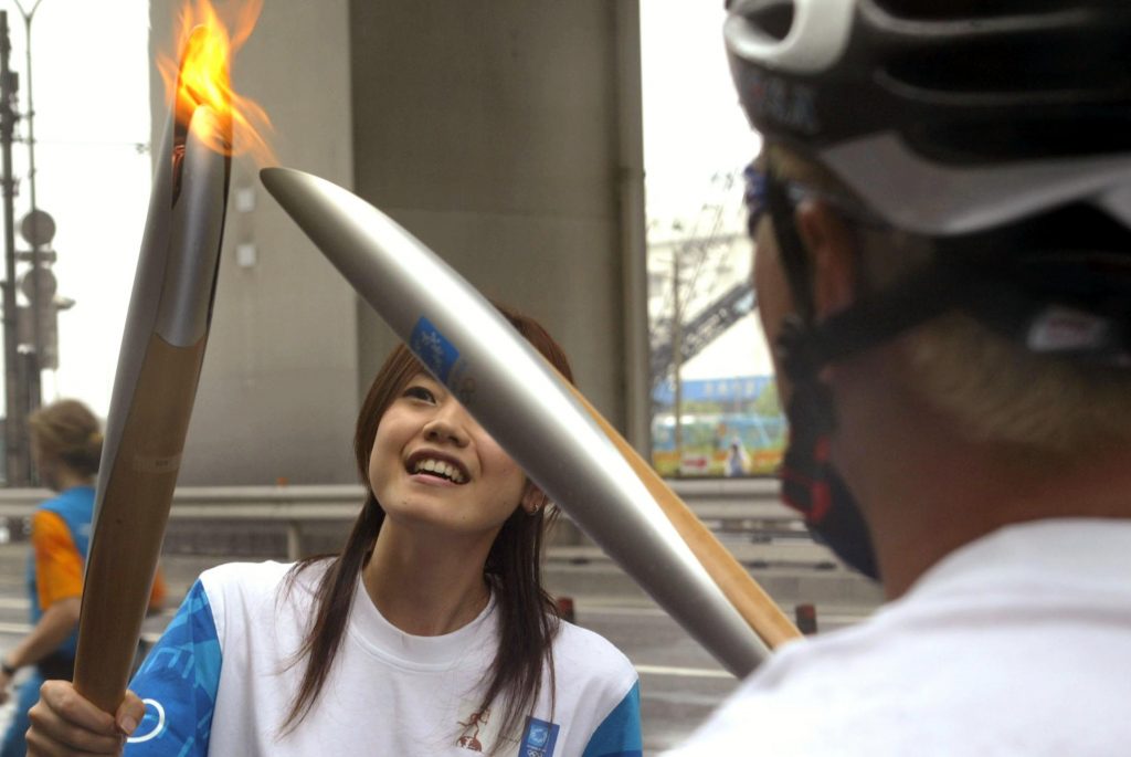Torchbearer Kouichi Nakano (R) passes the Olympic Flame to torchbearer Asami Kobayashi during day four of the Athens 2004 Olympic Torch Relay, 06 June 2004 in Tokyo. (File photo/AFP)