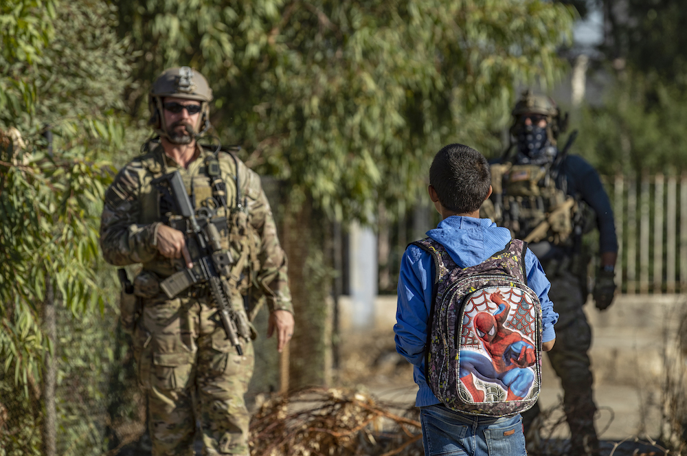 A Syrian boy looks at US troops on patrol in the village of Ein Diwar in Syria’s northeastern Hasakah province. (AFP)