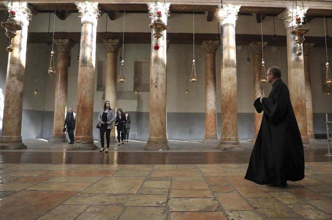 Visitors walk in the basilica at the Church of the Nativity, in the city of Bethlehem in the occupied West Bank, on Dec. 22, 2019. (AFP)