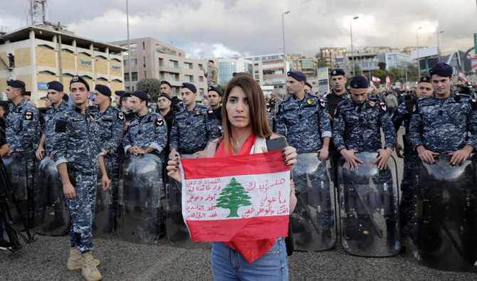 A Lebanese anti-government protester holds a national flag in front of members of the internal security forces as she takes part in a rally in Baabda near Beirut. (AFP)