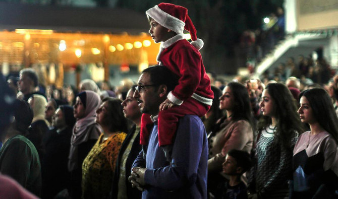 A Palestinian with his child attends a Christmas tree lighting event in Gaza City. (AFP)