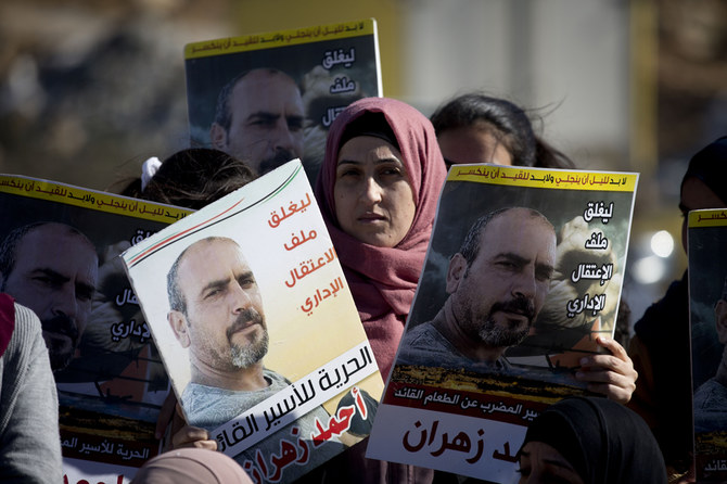 Karemah Zahran holds photograph of her husband Ahmed Zahran, who has been on a partial hunger strike for nearly three months, outside Ofer military prison near the West Bank city of Ramallah on Dec. 19, 2019. (AP Photo/Majdi Mohammed)