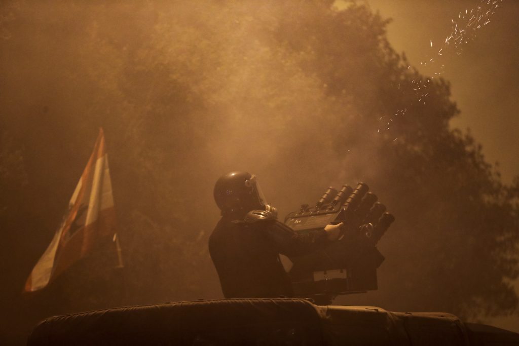 A Lebanese riot policeman fires tear gas canisters from a launcher during clashes with anti-government protesters in Beirut, Lebanon. (AFP)