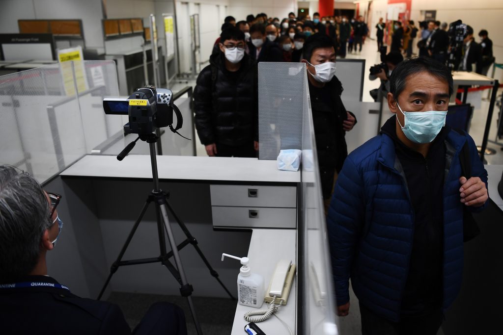 Passengers who arrived on one of the last flights from the Chinese city of Wuhan walk through a health screening station at Narita airport in Chiba prefecture, outside Tokyo, on Jan. 23, 2020. (AFP)