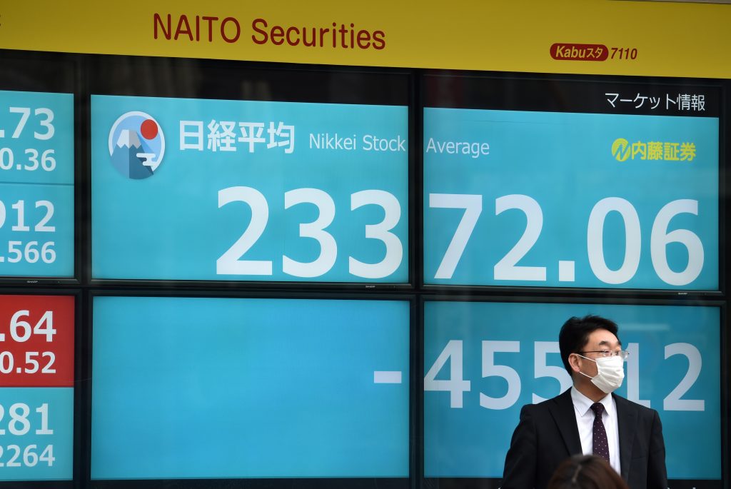 A pedestrian stands in front of an electric quotation board displaying the morning numbers on the Nikkei 225 Index on the Tokyo Stock Exchange, Tokyo, Jan. 27, 2020. (AFP)