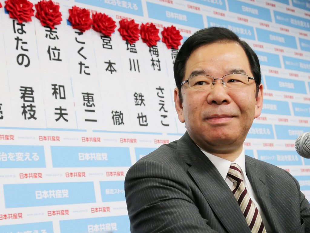 Japanese Communist Party leader Kazuo Shii smiles after placing roses on the names of his party candidates at the party headquarters in Tokyo on Dec. 14, 2014. (AFP)