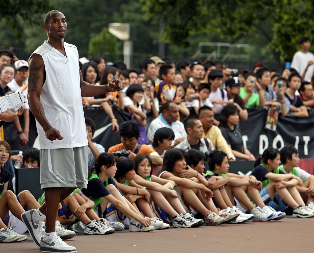 US NBA's Los Angeles Lakers star shooting guard Kobe Bryant (L) watches a game played by junior basketball players during his basketball clinic, 