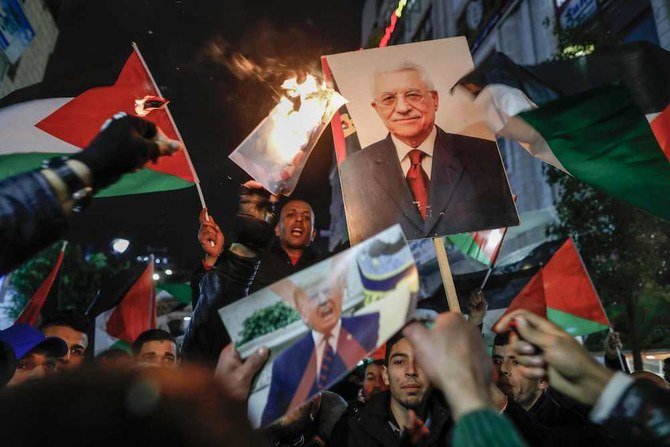 Palestinian protesters wave the national flag and a portrait of President Mahmoud Abbas during a demonstration in the West Bank city of Ramallah. (AFP)